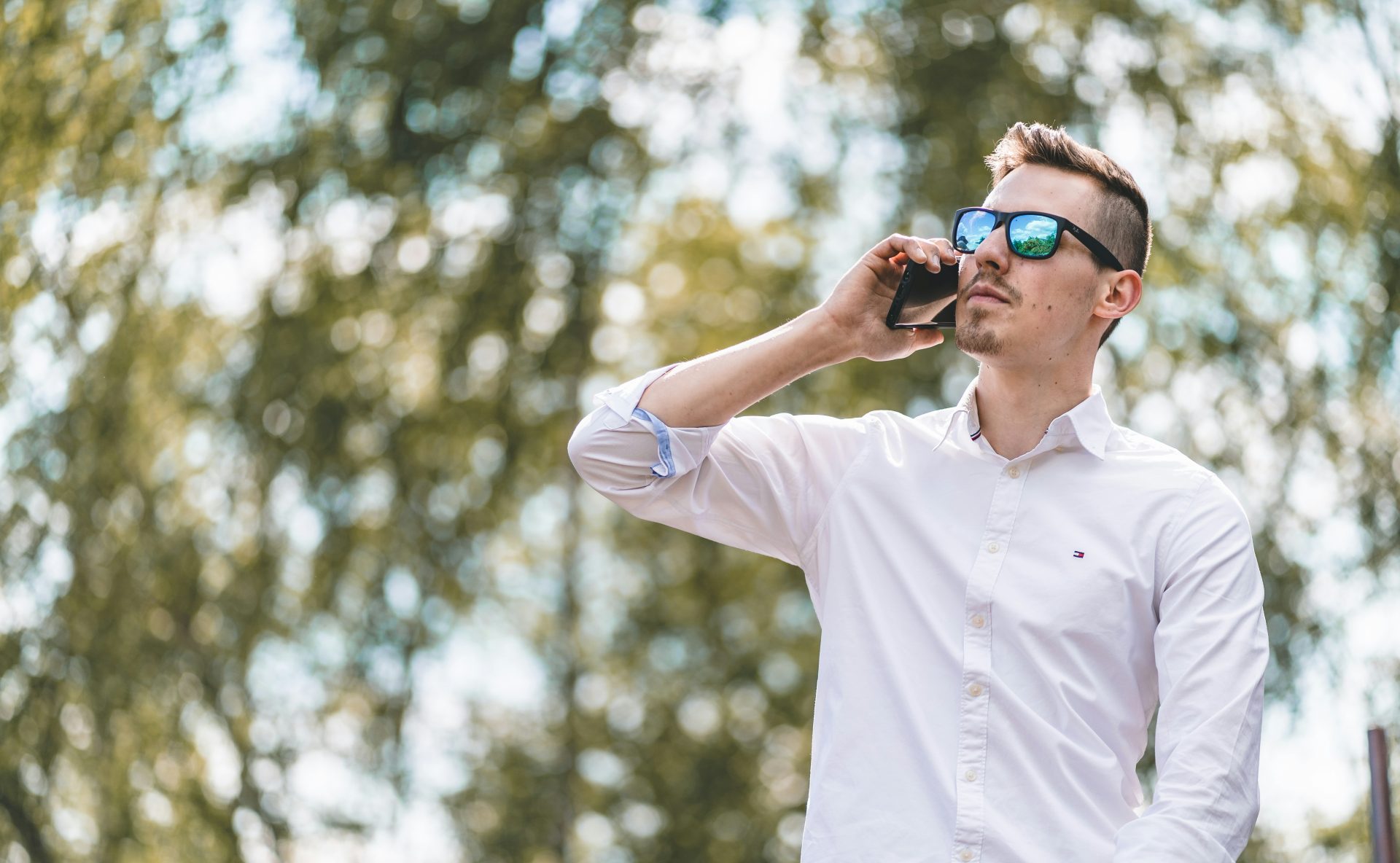 man in white polo shirt wearing blue sunglasses